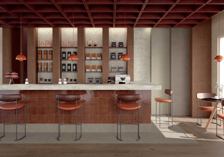 Moderne koffiebalie met terracotta tegels, houten krukken, hanglampen en planken met koffieproducten.